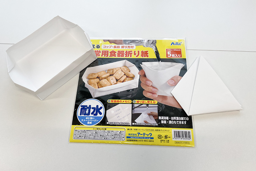 「非常用食器折り紙」のパッケージと、その両脇にその折り紙で作ったお皿とコップ
