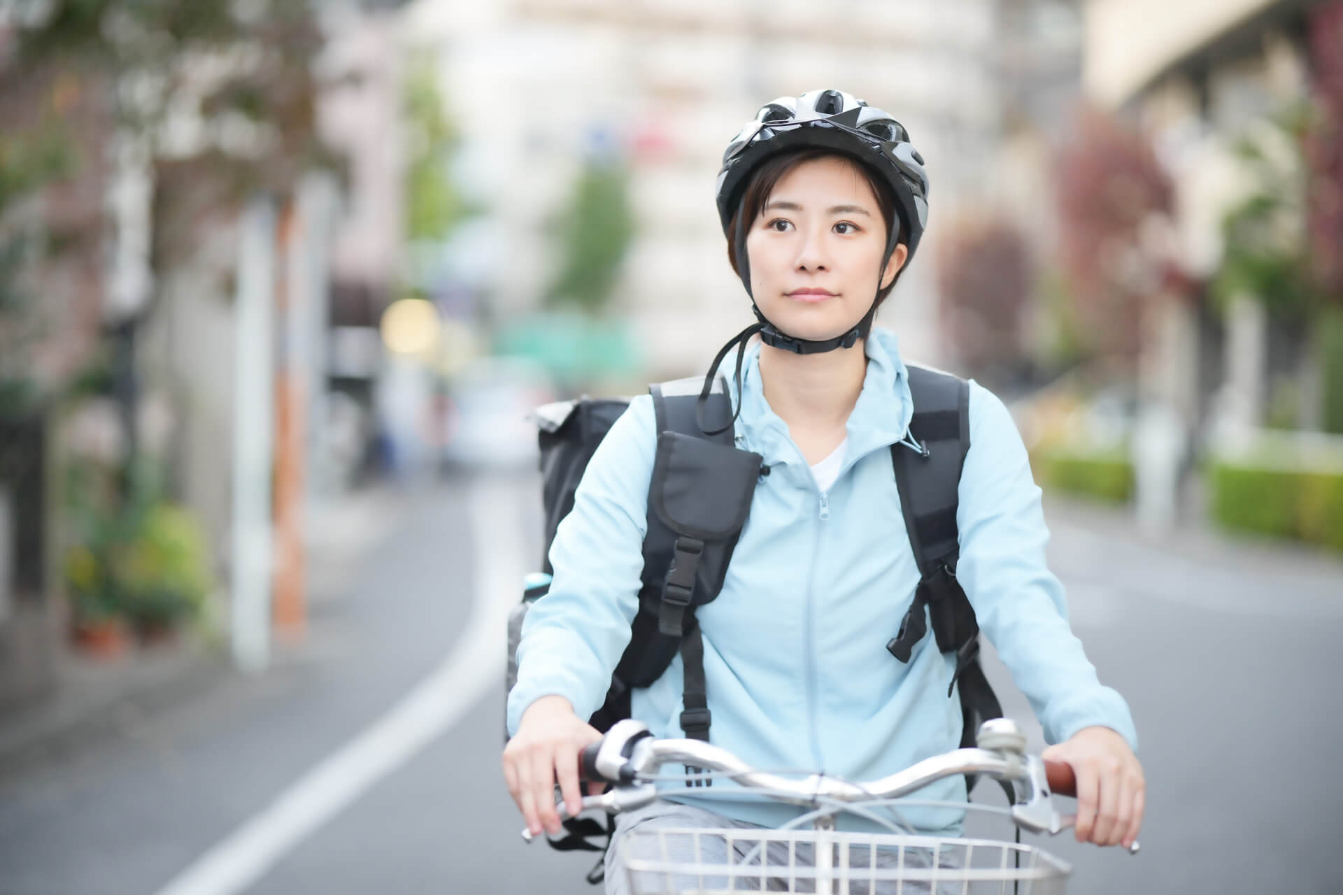 自転車用ヘルメットを被り自転車に乗る女性の画像。